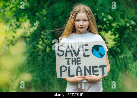 Kind Mädchen Aktivist mit retten den Planeten Poster im Waldpark. Preteen Kind Freiwilligen Kampf gegen Verschmutzung, Globale Erwärmung, Müll zu recyceln. Ecolog Stockfoto