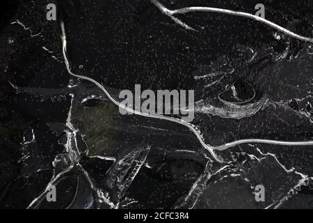 Fragment von dünnem Eis auf dunklem gefrorenem Fluss Stockfoto