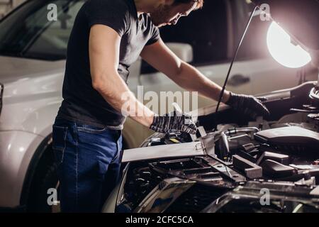 Mechaniker Fahrzeug Checkup durchführen und Notizen in Notepad machen in einer Garage. Stockfoto