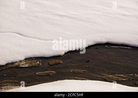 Auftauöffnung in schmelzender Eisschicht mit schneebedeckendem Wasser Strom im Frühjahr Stockfoto