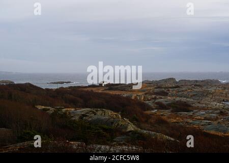 Glatte Felsbrocken an leerer Küste mit Meereswellen im Dunkeln Abendhimmel in Norwegen Stockfoto