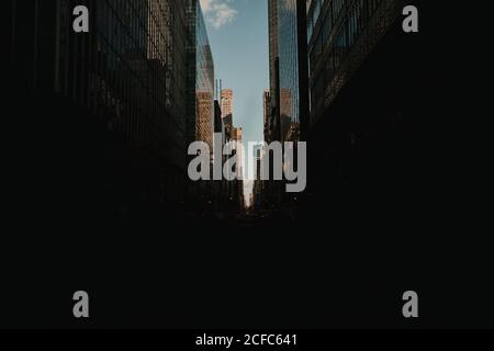 Perspektive dunkle Straße Blick zwischen glänzenden Glas Wolkenkratzern im Sonnenlicht, New York Stockfoto