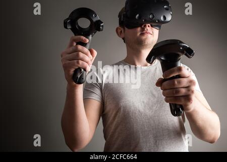 Mann mit der Virtual-Reality-Brille und zwei Gamepad Stockfoto