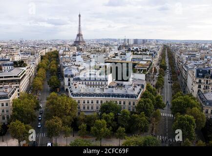 Blick vom Arc de Triomphe auf die malerische Stadt Paris mit Eiffelturm und grüne Straße unter bewölktem Himmel Stockfoto
