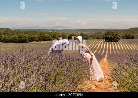 Seitenansicht des liebenden Paares, das sich einander zubeugt und Küssen beim Wandern auf blühenden lila Lavendel Feld im Sommer Tag Stockfoto