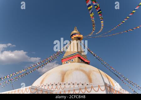 Niedriger Winkel der alten buddhistischen hemisphärischen Denkmal mit Ornament und Dekorative Augen auf Turm mit kleiner Kuppel und Girlanden auf Am Nachmittag oben unter dem Himmel Stockfoto