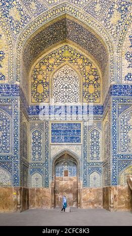 Seitenansicht einer muslimischen Frau, die in einer majestätischen iranischen Moschee steht Mit dekorativen Wänden mit bunten Mosaik und Buntglas bedeckt fenster Stockfoto
