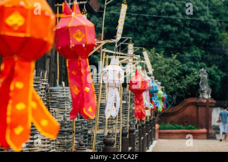Seitenansicht der bunten nationalen Laternen mit Ornamenten, die in Reihe auf dem Tempelhof in Thailand hängen Stockfoto