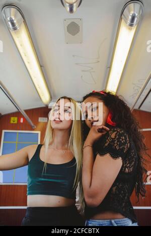 Fröhliche multirassische Frauen im Zugauto in Berlin beim Betrahen Kamera Stockfoto