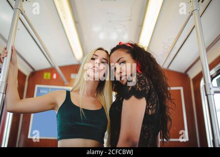 Fröhliche multirassische Frauen im Zugauto in Berlin beim Betrahen Kamera Stockfoto