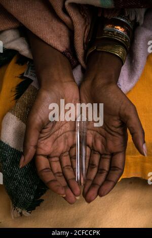 Von oben der Ernte anonyme ethnische Frau in traditioneller Kleidung Mit Metall Armbänder halten Glasrohr mit Räucherstäbchen für Spirituelle Zeremonie Stockfoto