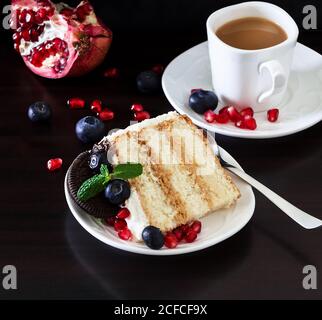 Tasse Kaffee und Stück Schichtenkuchen mit frischen Blaubeeren, Frischkäse und Schokoladenkeksen. Dunkler Holzhintergrund. Romantischer Valentinstag con Stockfoto