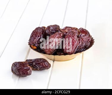 Bio getrocknete Datteln in traditionellen arabischen goldenen Teller. Konzept des Heiligen Monats Ramadan. Weißer Holzhintergrund. Stockfoto
