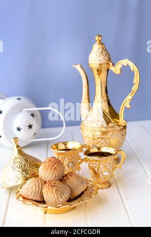 Ramadan-Konzept. Maamoul traditionelle arabische gefüllte Gebäck oder Plätzchen mit Datteln oder Nüssen serviert mit Kaffee goldenen Set. Süßes aus dem Osten. Nahaufnahme. Weiß wo Stockfoto