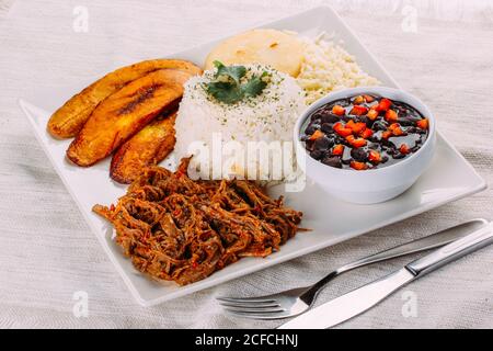 Hausgemachtes venezolanisches Essen. Traditionelles venezolanisches Gericht. Pabellon Criollo. Weißer Reis, schwarze Bohnen, gebratene Kochbananen und geschreddertes Rindfleisch Stockfoto