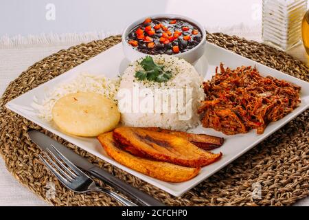 Hausgemachtes venezolanisches Essen. Traditionelles venezolanisches Gericht. Pabellon Criollo. Weißer Reis, schwarze Bohnen, gebratene Kochbananen und geschreddertes Rindfleisch Stockfoto