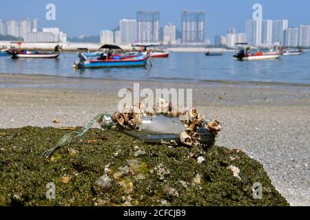 Eine Flasche mit einer Krone auf einer Felsenernte in einem städtischen Stadthafen mit traditionellen Fischerbooten im Hintergrund. Stockfoto