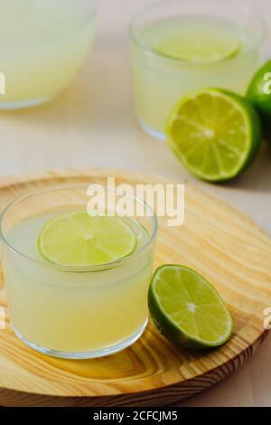 Von oben hausgemachte erfrischende Limonade im Kellner in Gläsern auf Holztablett in weißem Tischhintergrund Stockfoto