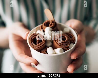 Gerolltes Schokoladeneis in Kegelbecher in Frauenhänden. Hand halten Kegelbecher mit thai-Stil Schokolade gewalzte Eis Stockfoto