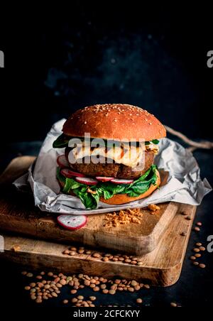 Linsen vegane Hamburger auf Holzbrett auf dunklem Hintergrund platziert Stockfoto