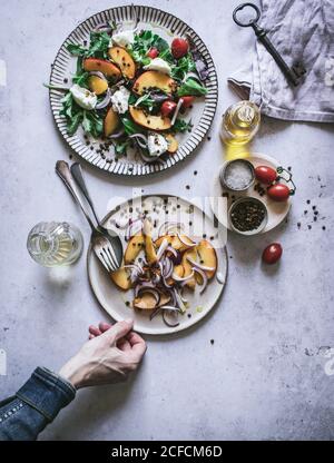 Von oben Ernte Hand des Menschen halten Teller mit Sommersalat aus Obst, Gemüse und Gewürzen Stockfoto