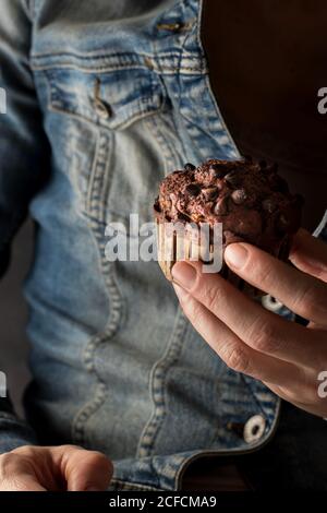 Nicht erkennbare Frau hält köstliche Schokolade Banane Muffin in der Hand in der Nähe Kamera Stockfoto