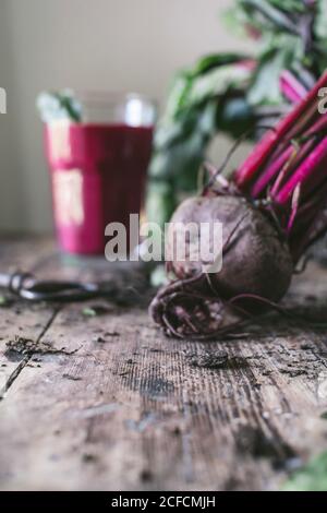 Weicher Fokus von Bio-Rote Bete mit Blättern und erfrischendem Lila Gemüsesaft im Glas auf schmutzigen rustikalen Holztisch platziert Stockfoto