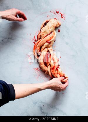 Von oben beschnitten unkenntlich Person Hände, die frische Erdbeer Brioche Auf einer Küche weißen modernen Marmortisch Stockfoto