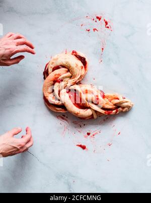 Von oben beschnitten unkenntlich Person Hände, die frische Erdbeer Brioche Auf einer Küche weißen modernen Marmortisch Stockfoto