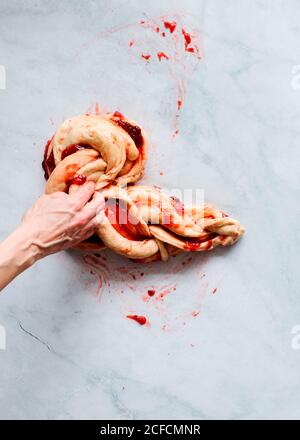 Von oben beschnitten unkenntlich Person Hände, die frische Erdbeer Brioche Auf einer Küche weißen modernen Marmortisch Stockfoto