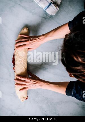Von oben beschnitten unkenntlich Person Hände, die frische Erdbeer Brioche Auf einer Küche weißen modernen Marmortisch Stockfoto