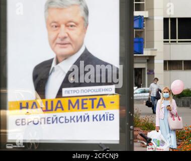 Kiew, Ukraine. September 2020. Eine Frau, die vorsichtshalber eine Gesichtsmaske trägt und einen Ballon in der Hand hält, der neben einem Transparent mit einem Foto des ehemaligen ukrainischen Präsidenten Petro Poroschenko steht. Kredit: Pavlo Gonchar/SOPA Images/ZUMA Wire/Alamy Live Nachrichten Stockfoto