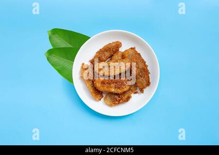 Gebratene Bananen mit Sesam auf weißem Keramik-Rundteller auf blauem Hintergrund. Draufsicht mit Kopierbereich Stockfoto