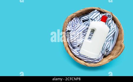 Kleidung mit Plastikflasche Waschmittel im Wäschekorb auf blauem Hintergrund. Speicherplatz kopieren Stockfoto