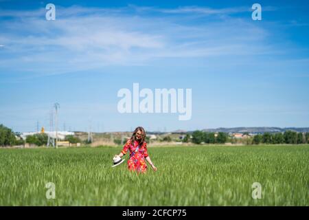 Junge Frau, die auf dem Feld einen Hut wirft Stockfoto