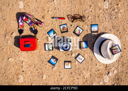 Verschiedene trendige Accessoires und Haufen von Instant-Bilder herum platziert Fotokamera auf sandigen Boden an sonnigen Sommertagen Stockfoto