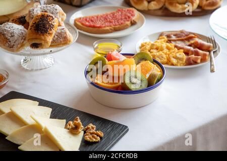 Von oben Teile von Orangen und Grapefruits und Kiwi Auf stilvoller Tischunterlage mit weißer Bettwäsche Stockfoto