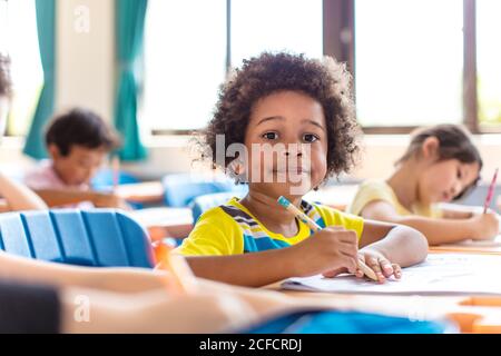 Lächelnder kleiner Junge, der im Klassenzimmer studiert. Stockfoto