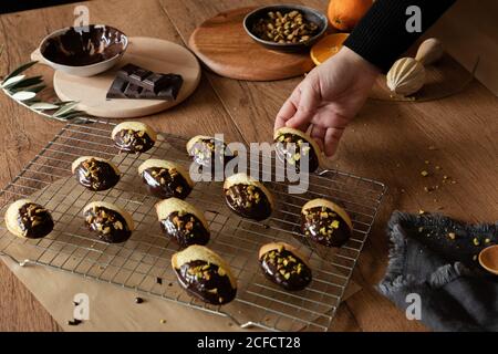 Von oben der Ernte Hand der weiblichen Putting lecker frisch Hausgemachte Madeleine mit Schokolade und Nüsse auf Küche Grill auf Holztisch Stockfoto