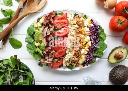Von oben sortierte Gemüse mit gebratenem Fleisch und Käse platziert Auf ovaler Platte auf weißer Tischplatte Stockfoto