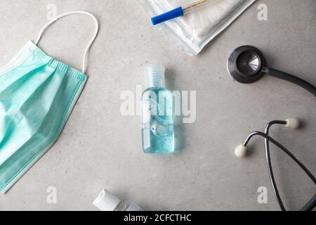 Draufsicht des antibakteriellen Gels für Coronavirus Prävention auf dem Tisch mit Gesichtsmaske, Thermometer und Stethoskop platziert Stockfoto