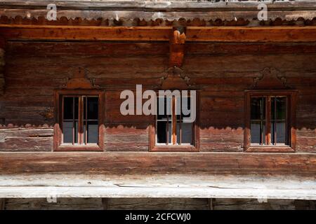 Drei kleine Fenster in der Holzbalkenwand eines Berghof auf dem Zimmererberg Stockfoto