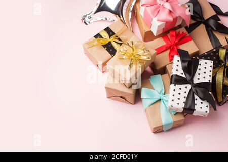 Holiday Set Geschenk Geschenkschachteln in Bastelpapier verpackt und mit Schleifen auf rosa Hintergrund gebunden, mit Konfetti verziert. Geburtstag, Weihnachten, Neujahr Stockfoto