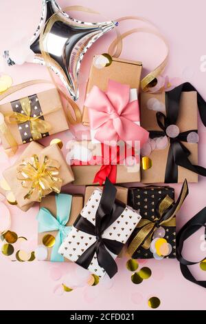 Holiday Set Geschenk Geschenkschachteln in Bastelpapier verpackt und mit Schleifen auf rosa Hintergrund gebunden, mit Konfetti verziert. Geburtstag, Weihnachten, Neujahr Stockfoto