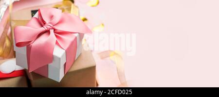 Holiday Luxury stilvolle Geschenk Geschenkbox mit rosa Schleife auf rosa Hintergrund gebunden, mit Konfetti verziert. Geburtstag, Weihnachten, Neujahr, Muttertag, Sal Stockfoto