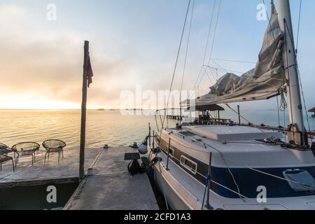 Segelboot auf dem Steg bei Sonnenaufgang über der Bacalar Lagune, Quintana Roo, Yucatan Halbinsel, Mexiko Stockfoto