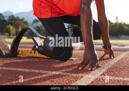 Niedriger Abschnitt des männlichen Athleten mit prothetischen Beinen biegen auf Startblöcke Stockfoto