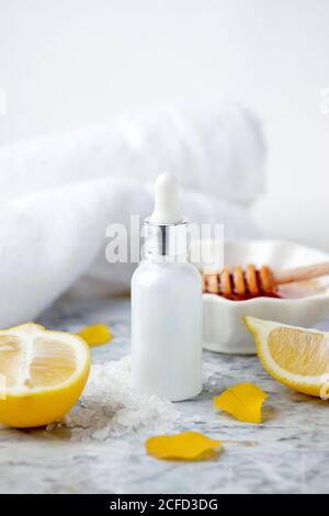 Hautpflege Naturprodukte Inhaltsstoffe für Peeling Körpermaske: Honig, Zitronensaft, Salzzucker, Glasflasche mit Tropf auf Marmorplatte, handgemachte Wellne Stockfoto