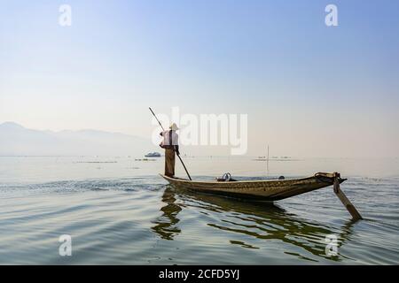 Fischer auf kleinem Boot mit langem Stock zum Angeln auf Inle Lake, Heho, Myanmar Stockfoto