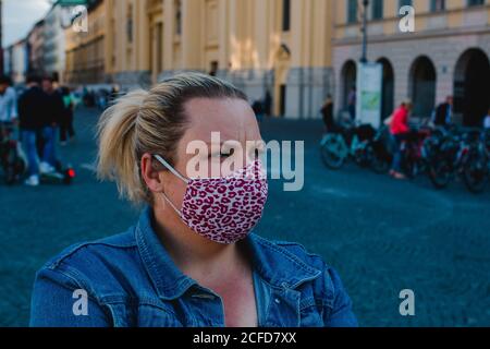 Blonde Frau mit Maske in Corona Times auf vollem Odeonsplatz In München Stockfoto